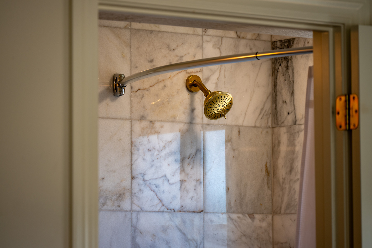 Polished fixtures and richly veined tile lend an elevated, spa-inspired finish to this beautifully appointed shower.