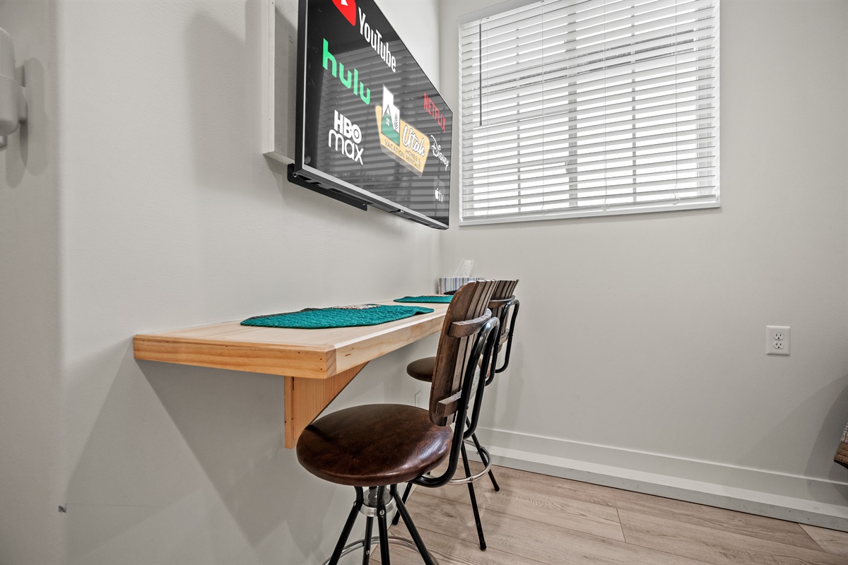 Bright studio dining nook with breakfast bar and Smart TV — ideal for enjoying meals