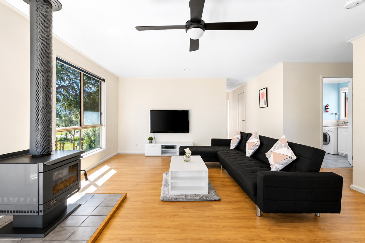 Relax in the main lounge at Carlenes Getaway, with reverse-cycle air conditioning, a ceiling fan and fireplace comfort for Loch Sport’s changing seasons