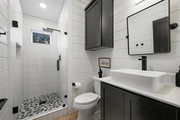 A glass walk-in shower with a rainfall showerhead adds a spa-like touch to the loft bathroom