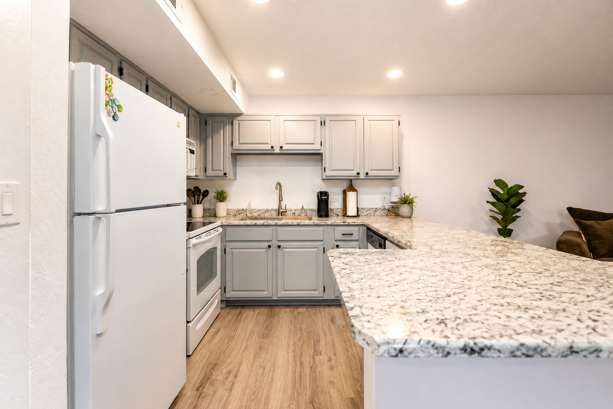 Kitchen with gray cabinets, full appliances, and a wide counter for meals or serving.
