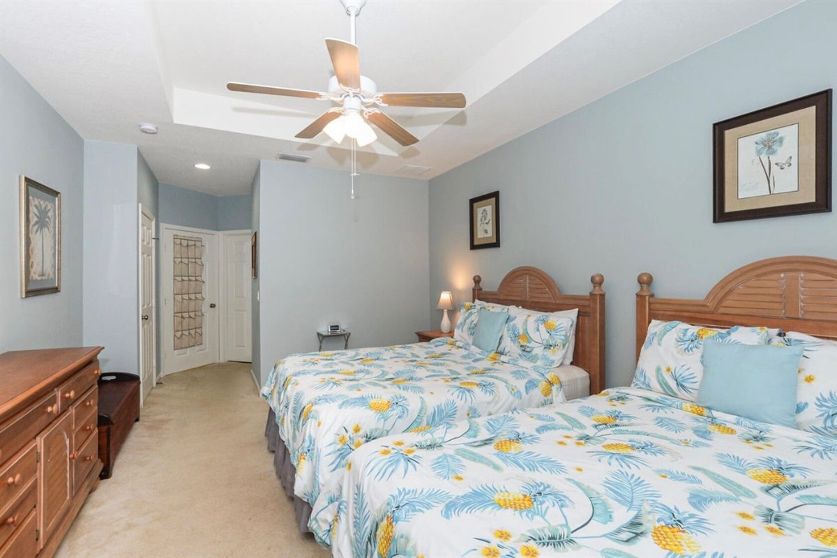 Spacious bedroom with a large bed, ceiling fan, dresser storage, and a relaxing neutral layout.
