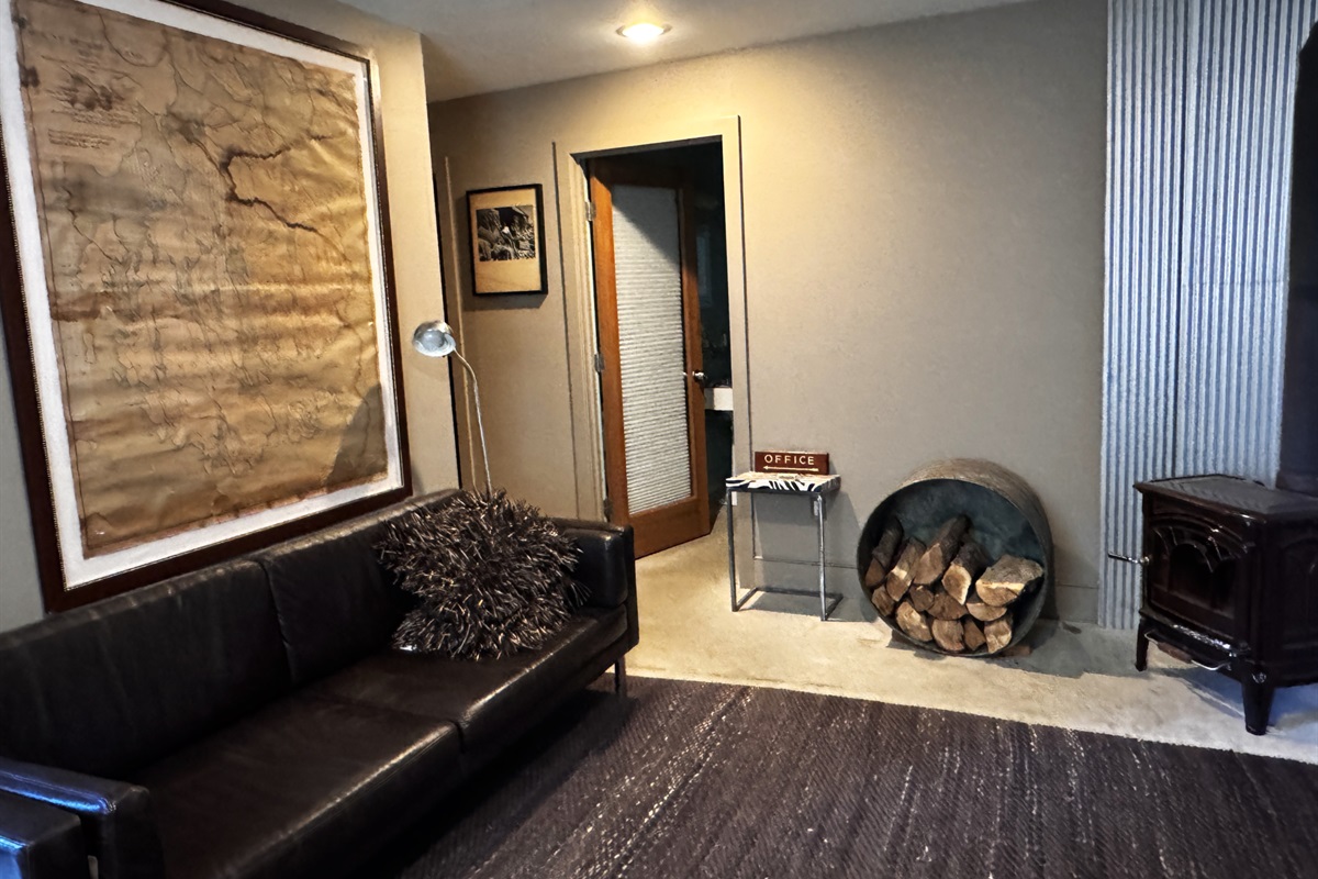 Lower level living area looking toward the dedicated guest bathroom and hallway leading to the twin guest room. This layout creates a private, self-contained suite for kids or secondary groups, away from the main level social hubs.