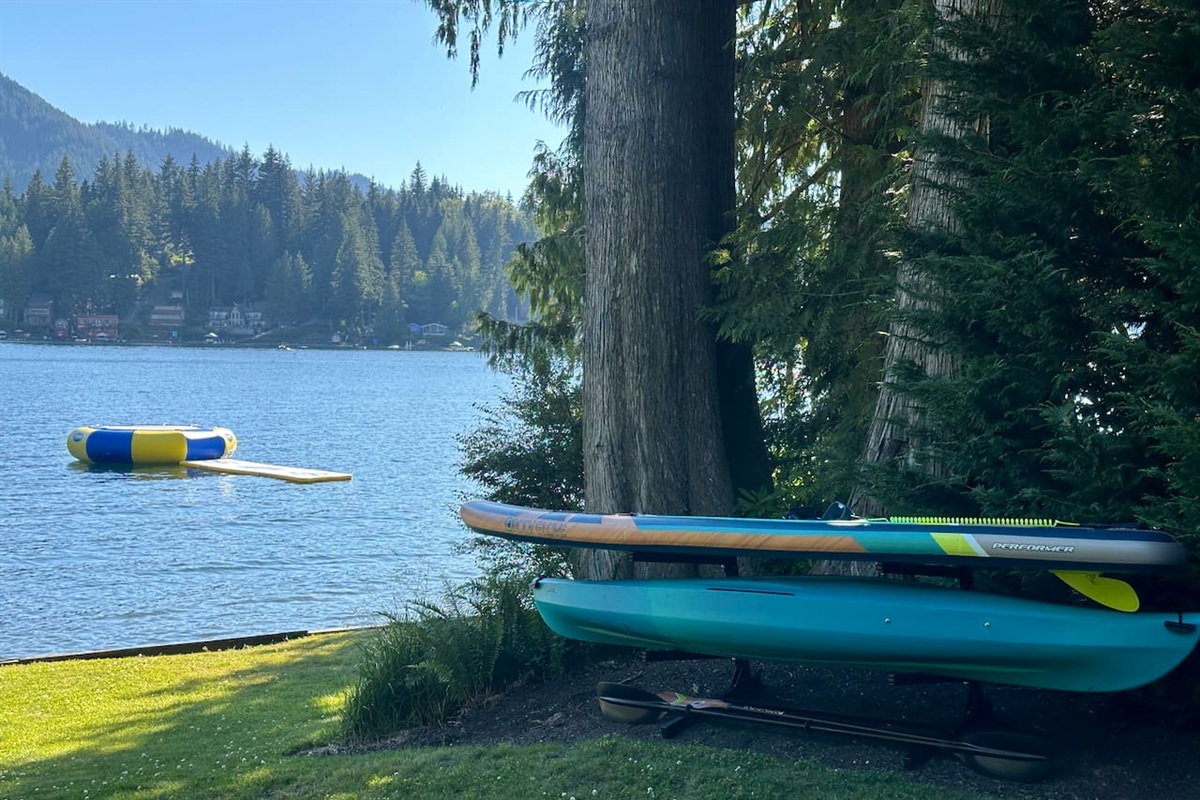 Two kayaks, two paddleboards, a water mat, and a water trampoline — all ready for fun on the lake.