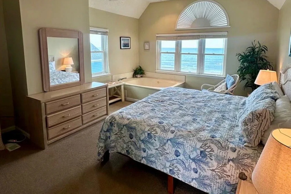 Primary bedroom with dresser and ocean-view windows