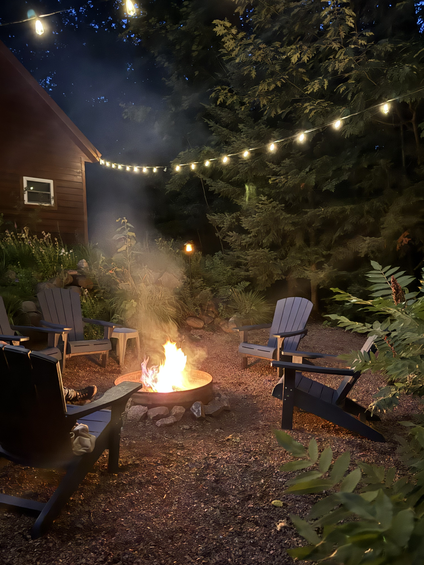Evening Rock Garden Cottage campfire, provided wood. Solar string lights at dusk above firepit and rock garden for a relaxing ambiance. 