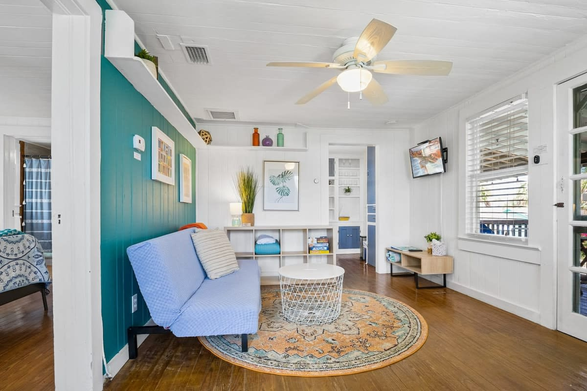 The teal wall and wide plank floors give the living room its character. Curl up with a book, put a film on the smart TV, and listen to the fans turning while somebody else worries about what time it is getting to be.