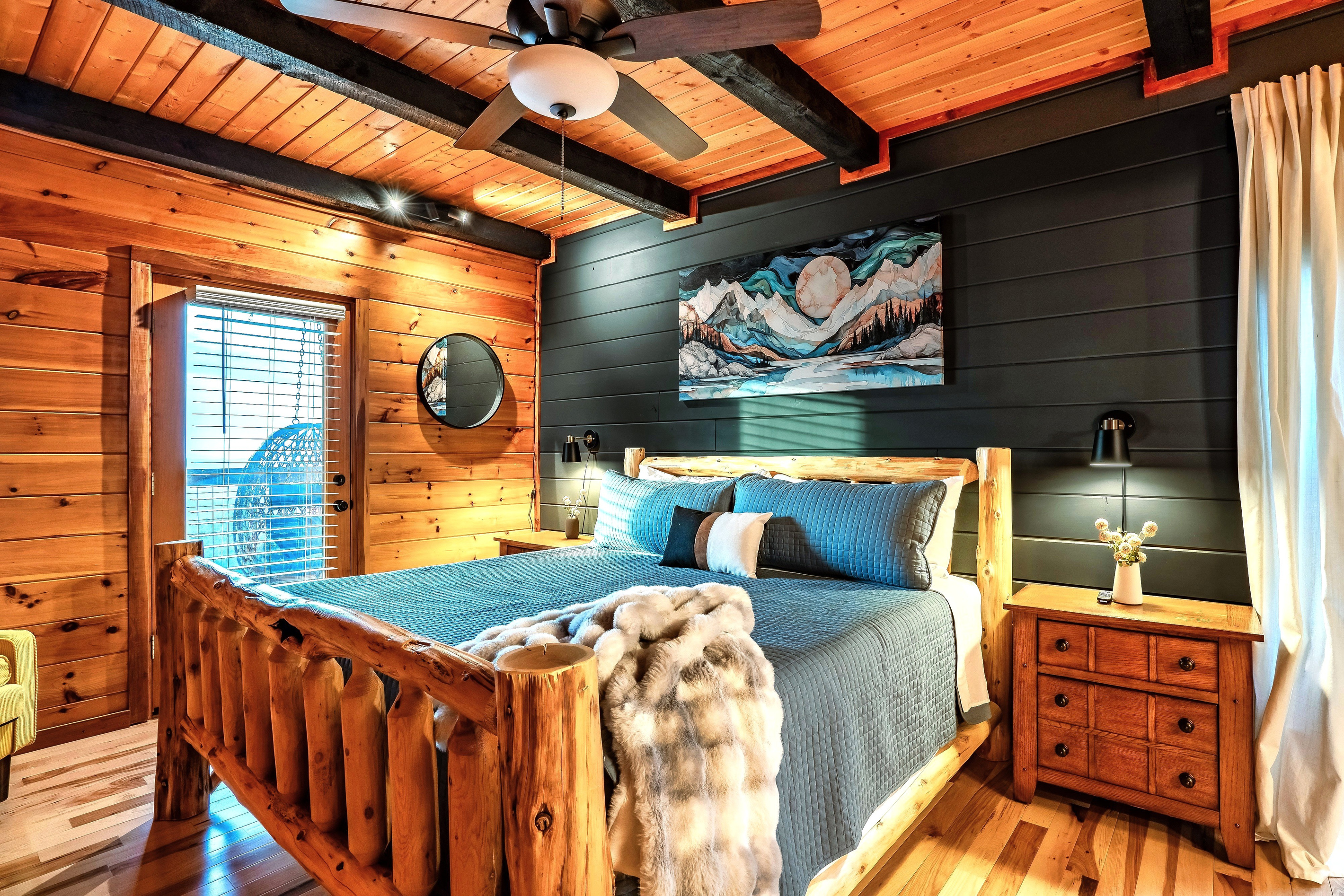 Subtle touch and design for a warm inviting master suite in a contemporary mountain cabin with darkened accent wall and direct access to the deck for unwinding.
