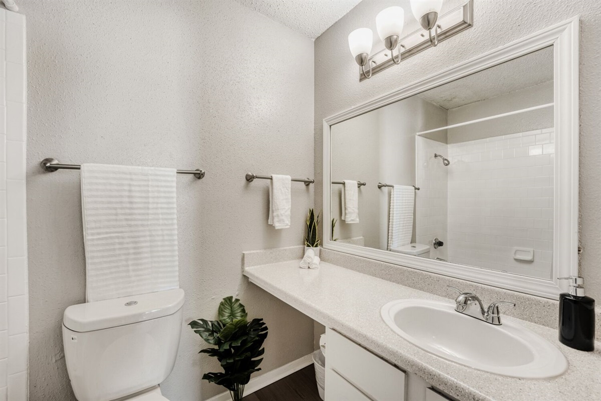 Bright modern bathroom with a large mirror, sleek vanity, and fresh white accents.