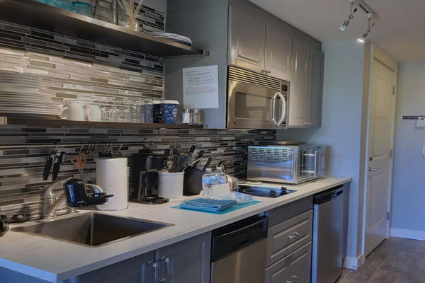 Kitchenette with cooktop, countertop oven, microwave, dishwasher and essentials.
