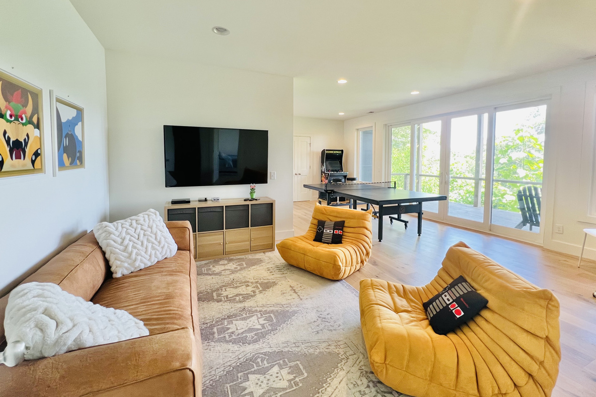 Game on.
The lower-level rec room is designed for fun, featuring a large Smart TV, arcade game console, ping pong table, comfortable seating, and direct access to a covered deck overlooking Lake Santeetlah.