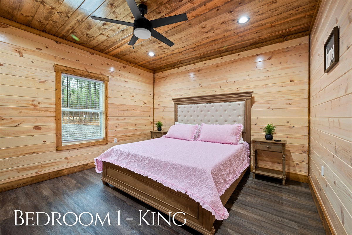 This inviting king bedroom offers a comfortable and peaceful place to recharge, with warm wood walls, soft lighting, and plenty of space to settle in after a full day exploring the area.