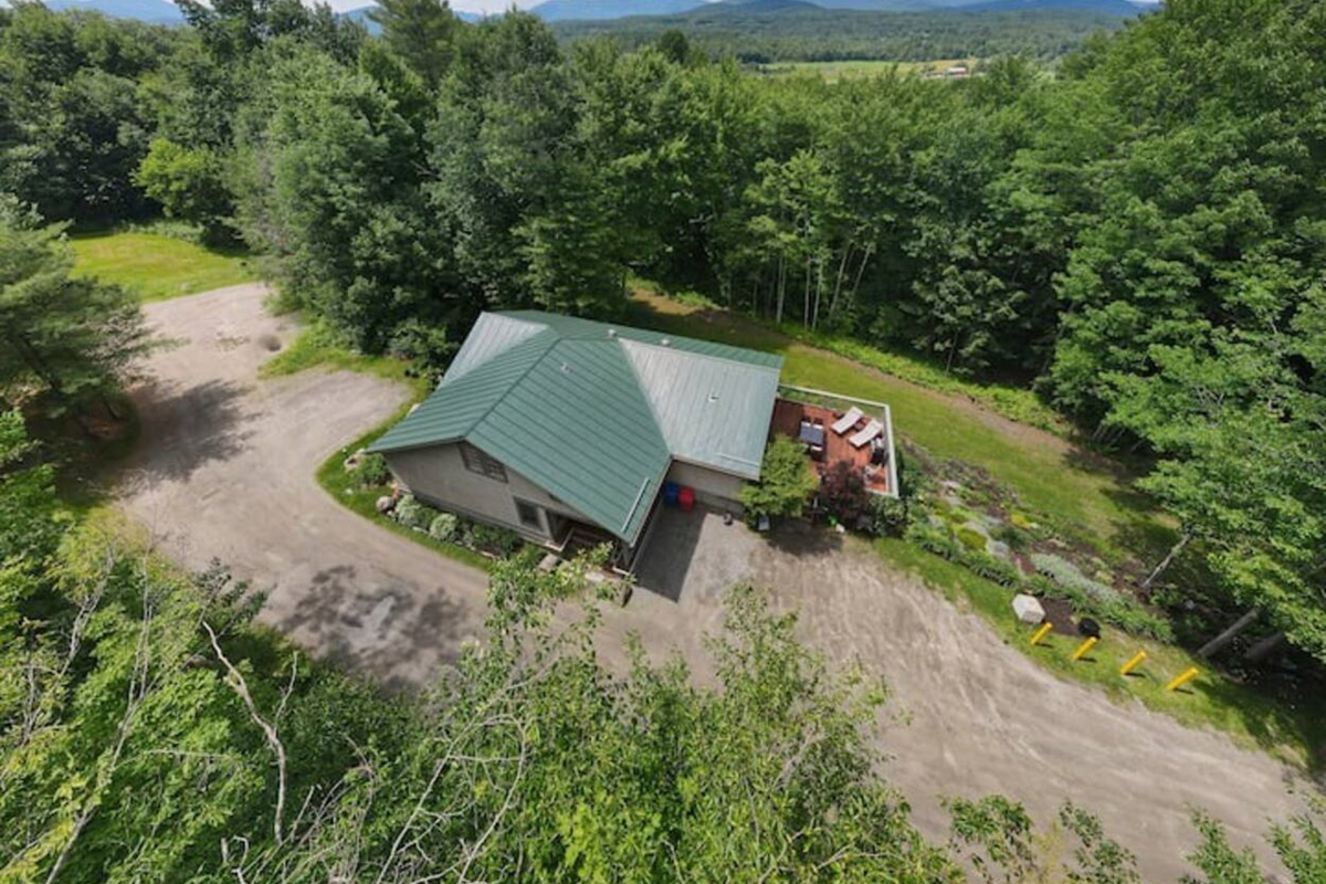 Aerial view of the house. Parking is in the area to the left, with outside stairs descending to the entrance at the lower level from there.