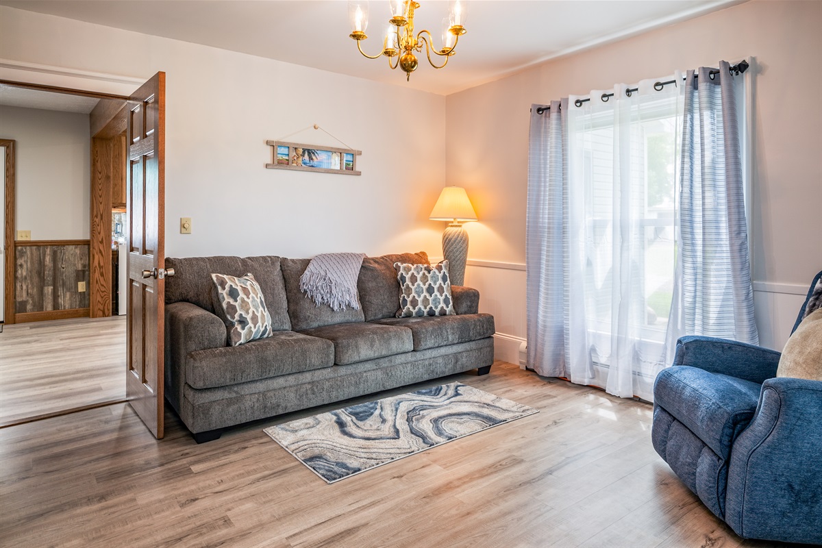 Cozy, sunlit living room with a plush queen fold out sofa sofa, elegant floor lamp, and modern wood flooring – perfect for relaxing in comfort and style.