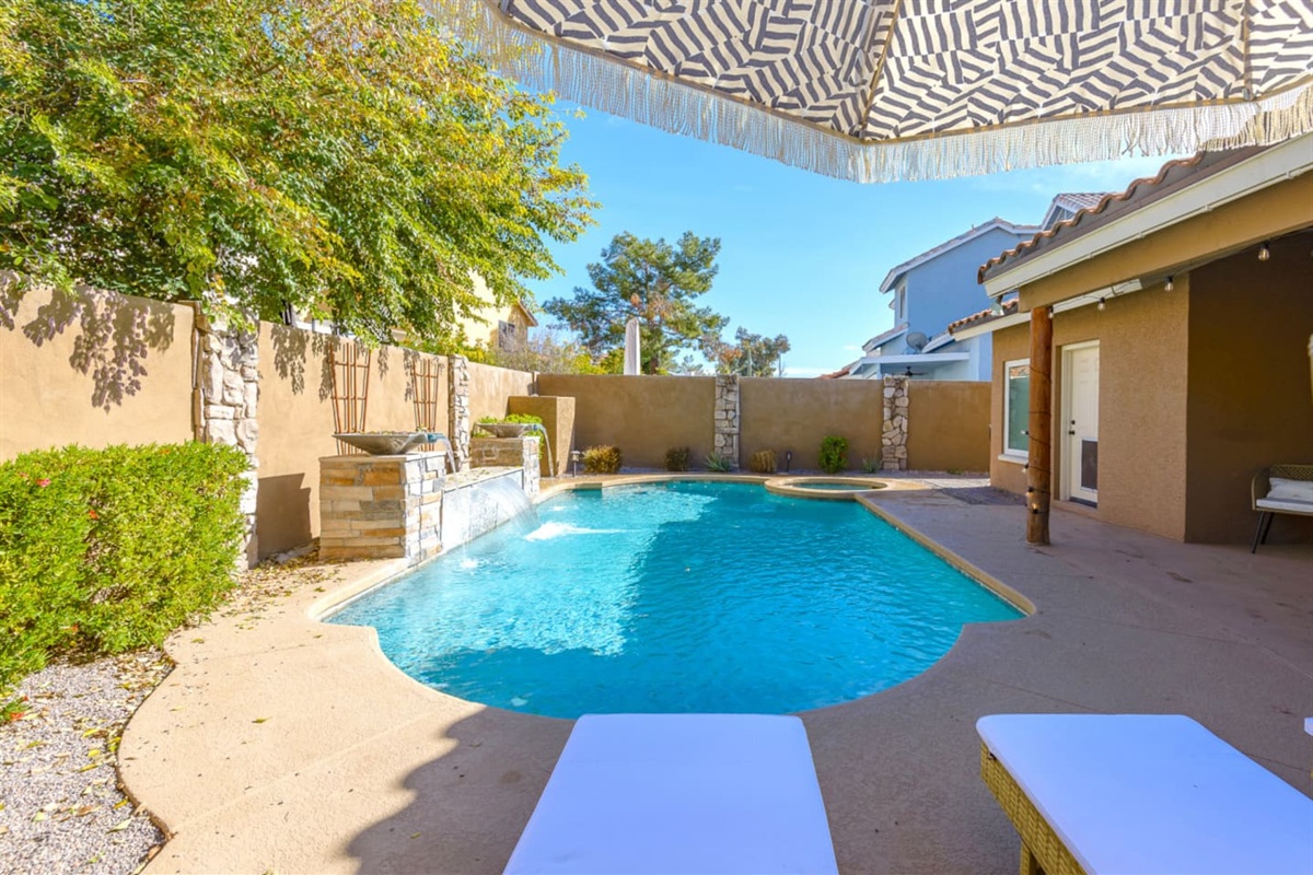 Poolside lounge area with seating, umbrella shade, and a tiki-style bar for sunny outdoor downtime.