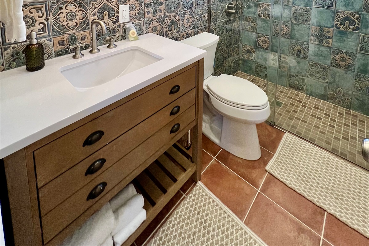 Refresh in the sparkling clean, modern bathroom, featuring a walk-in shower with a river rock floor and a relaxing rainfall showerhead.