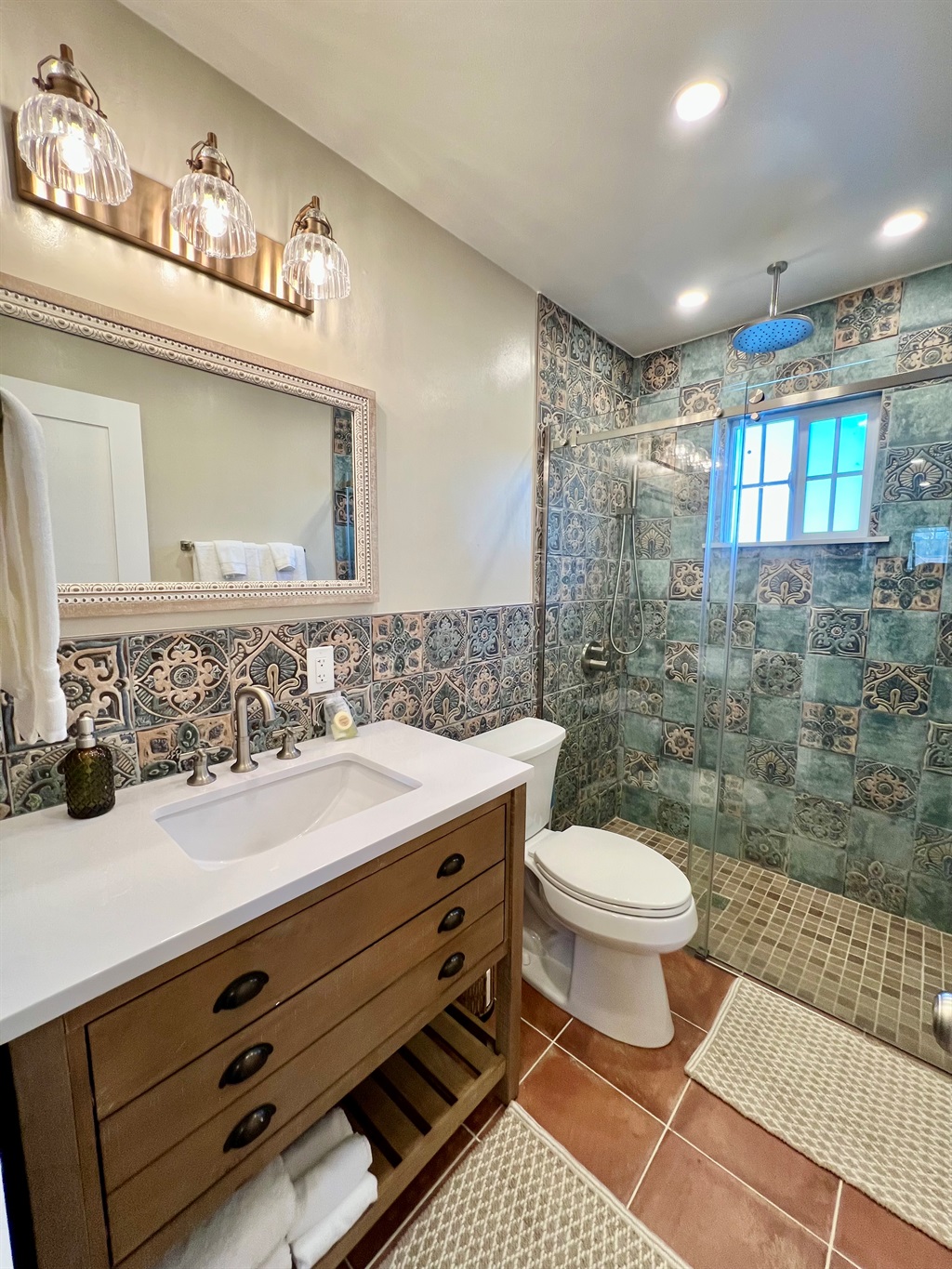 Refresh in the sparkling clean, modern bathroom, featuring a walk-in shower with a river rock floor and a relaxing rainfall showerhead.