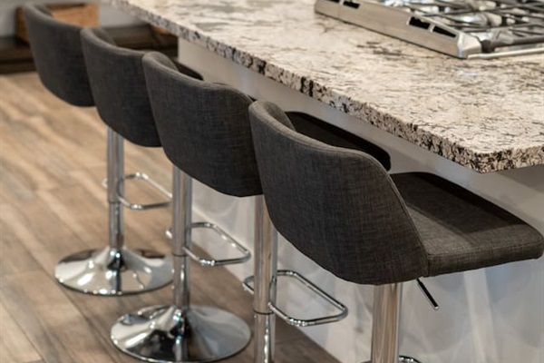 Modern kitchen countertop with a four-seater dining setup, featuring granite surfaces and sleek barstools for a stylish and functional dining experience.