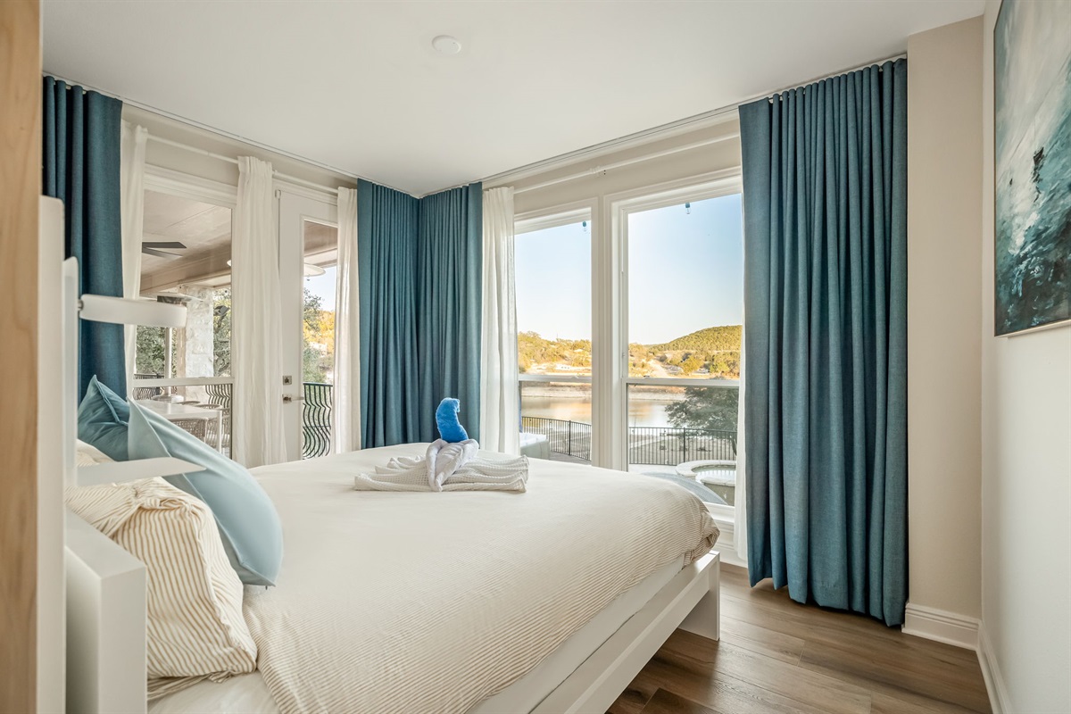 Bright and airy lakeview bedroom with large windows, plush bedding, and peaceful natural light.
