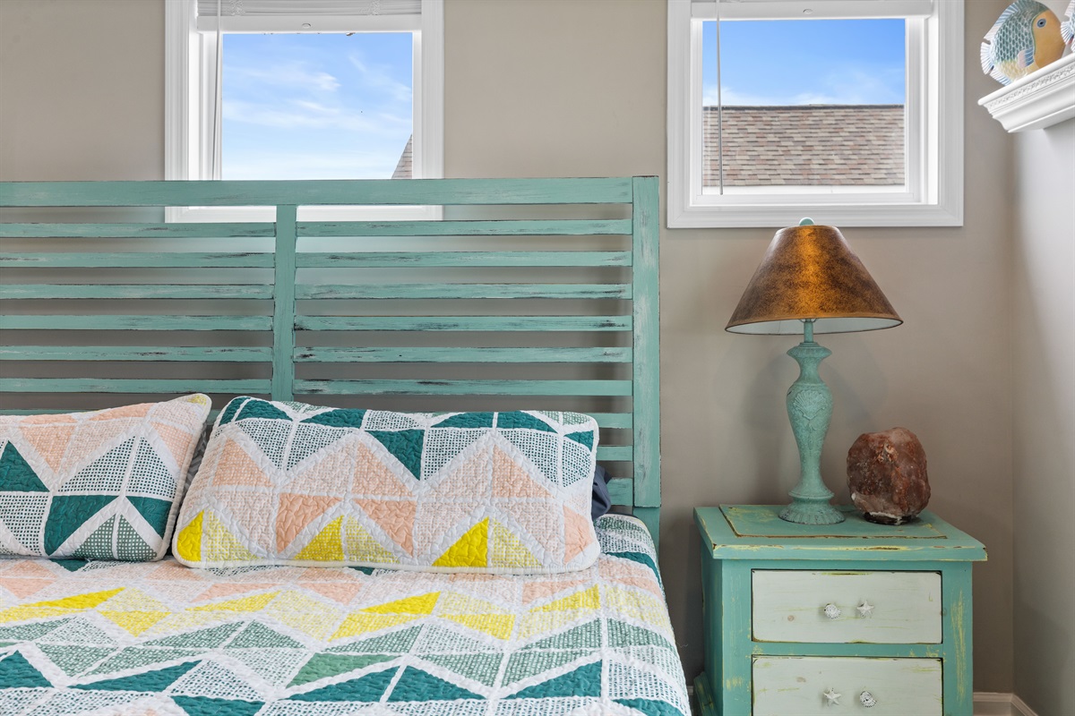 Cozy coastal king bedroom with charming pastel decor and natural light