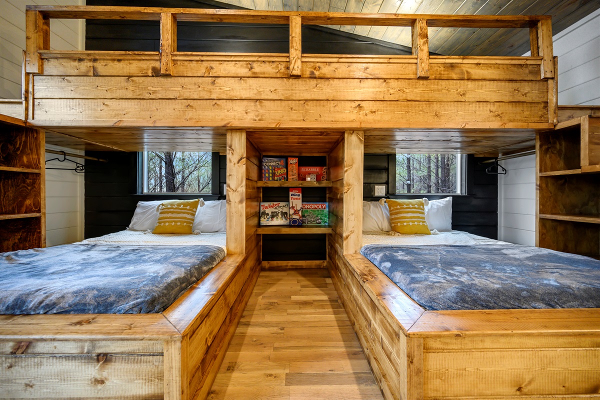 A fun bunk room made for groups — featuring twin beds with a connected upper bunk, side stairs, and lower bunks for extra sleeping space. A central game area with board games makes it perfect for bonding and fun nights in. 🎲