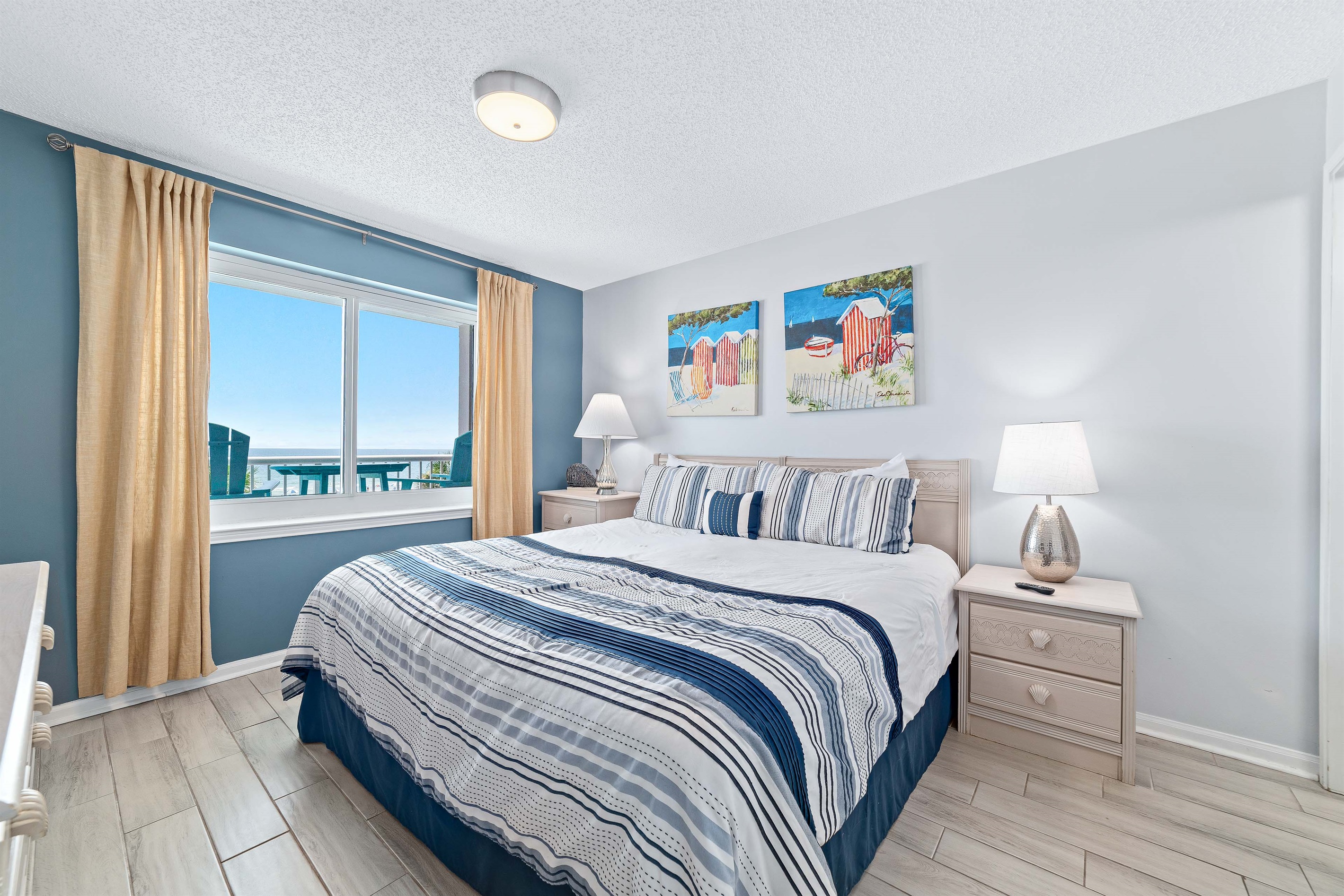 This well-appointed Primary bedroom features a king-size bed with a decorative headboard, crisp white bedding, matching nightstands with lamps, and tile flooring for easy maintenance.
