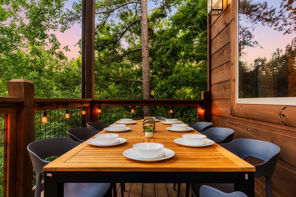 Enjoy dining on the outdoor deck with string lights surrounded by nature