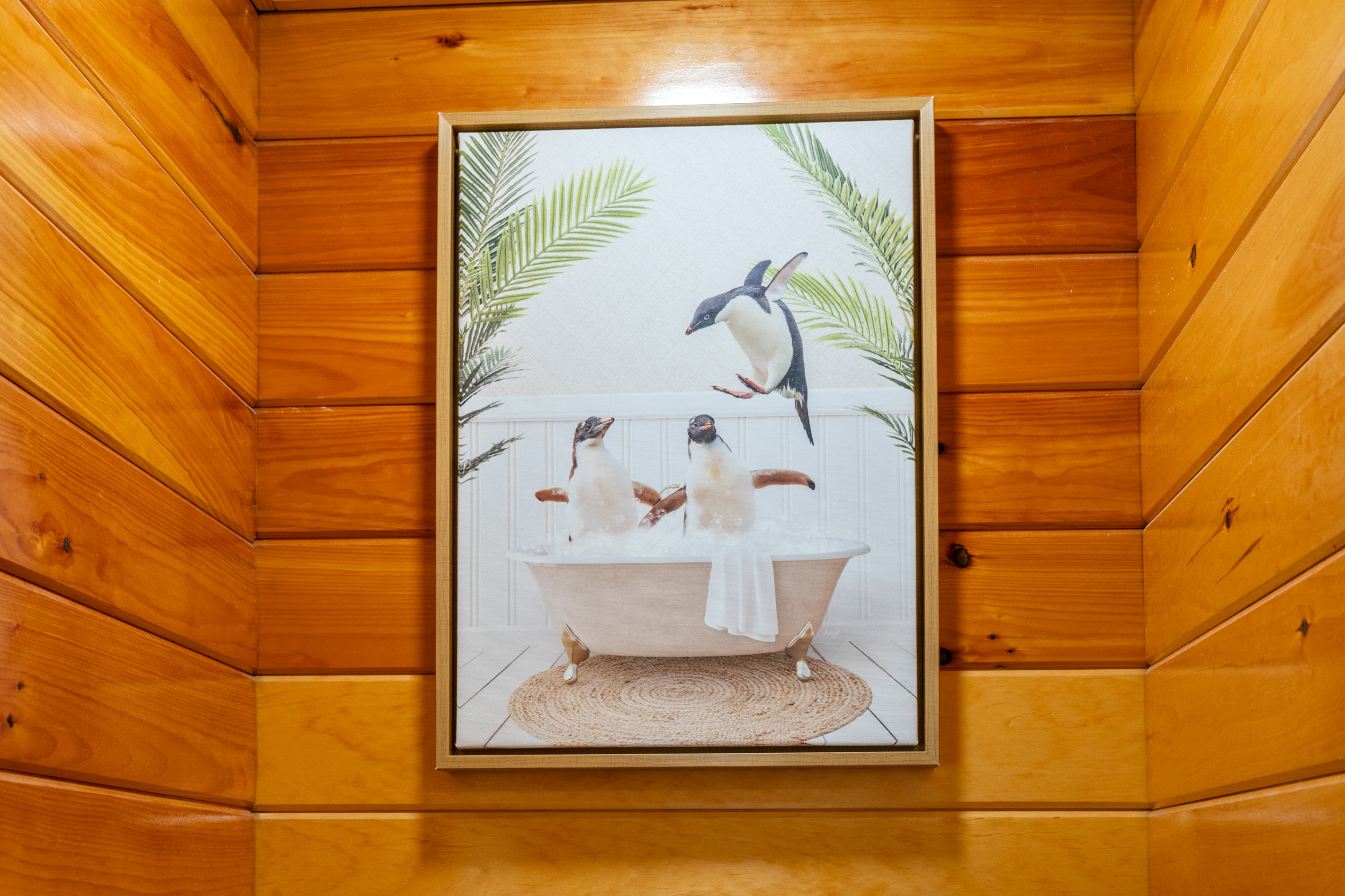 Enjoy the playful, whimsical charm added by this framed penguin bathtub art print. Mounted securely over the toilet alcove area, this fun piece complements the warm wood paneling while showcasing the home’s thoughtful design touches.