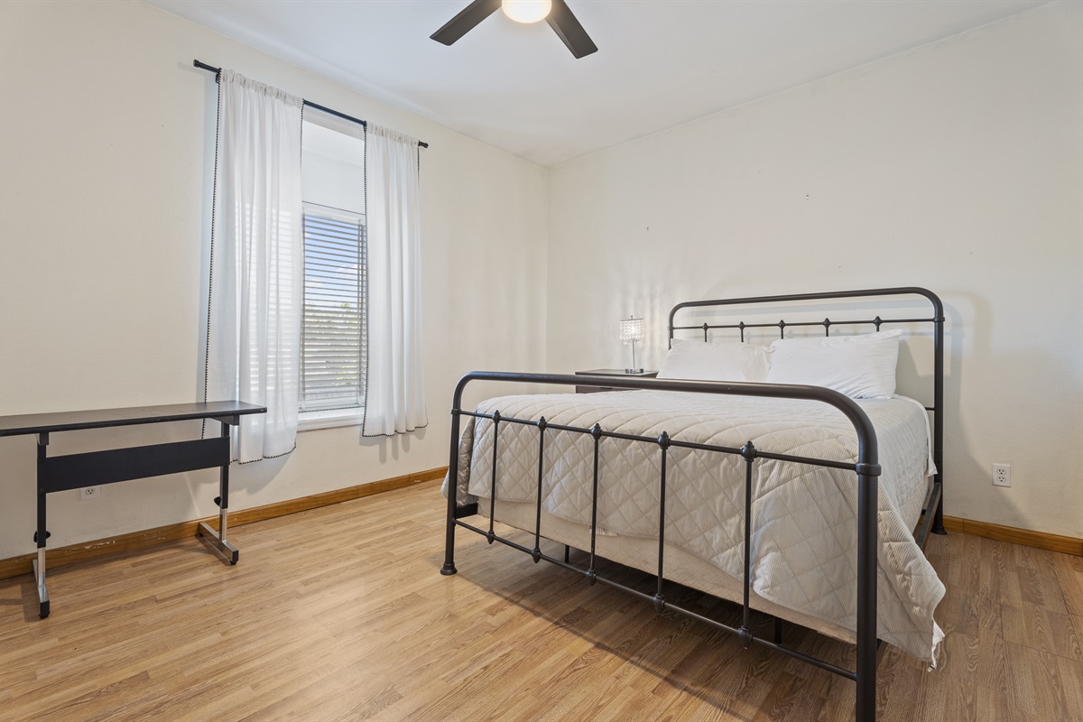 This sun-drenched bedroom blends modern simplicity with cozy charm, offering a metal-frame bed and a restful ambiance.