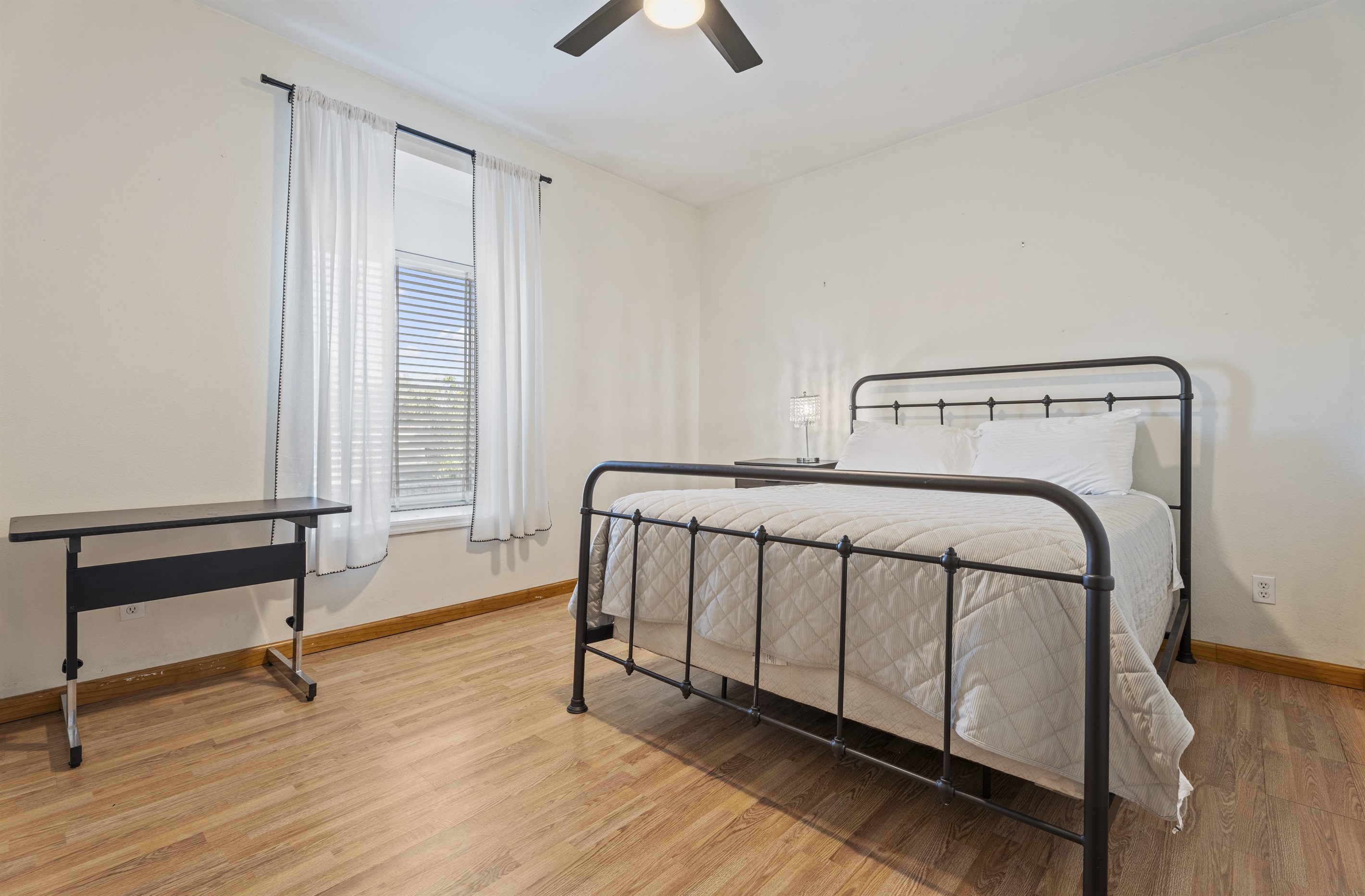 This sun-drenched bedroom blends modern simplicity with cozy charm, offering a metal-frame bed and a restful ambiance.