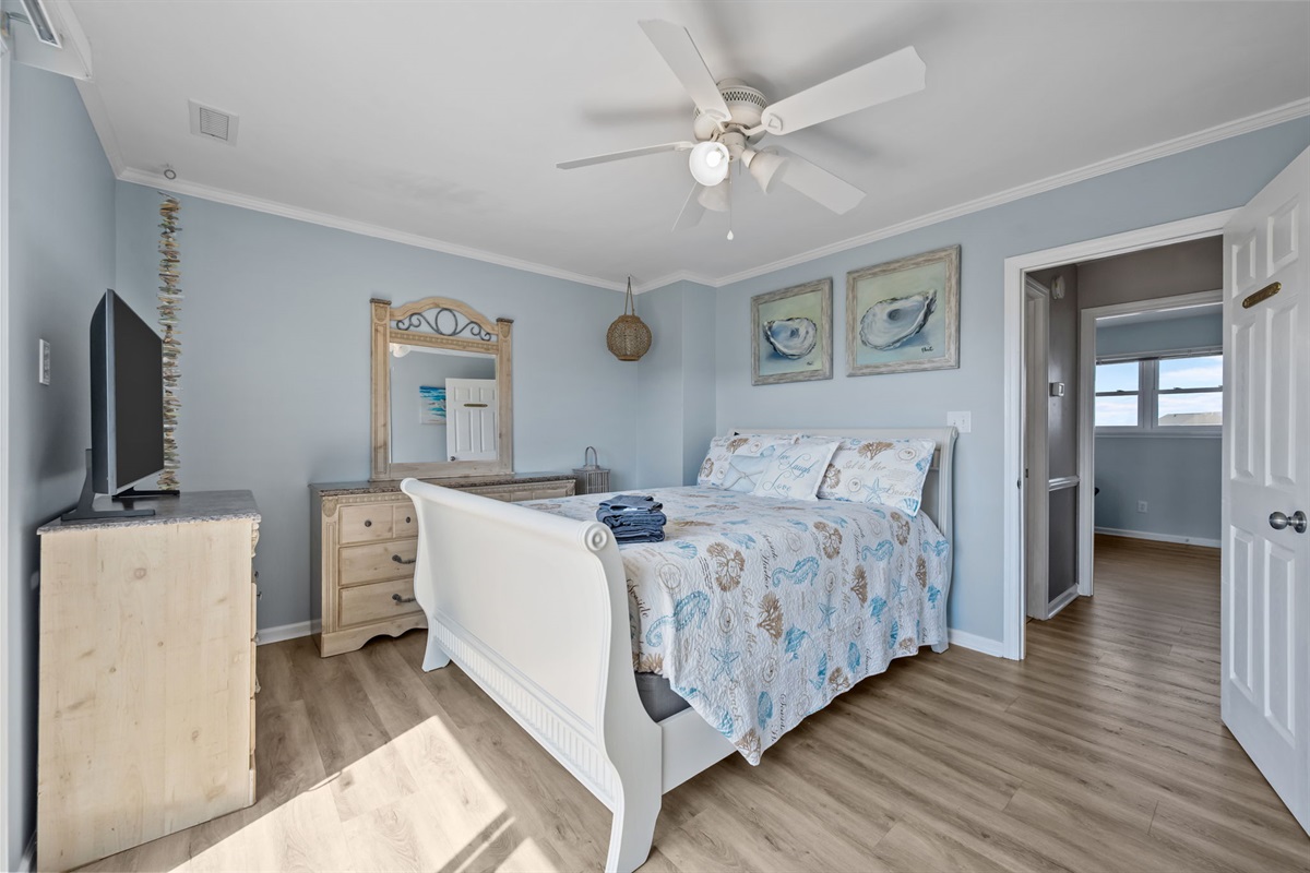 Spacious master bedroom with dresser and TV