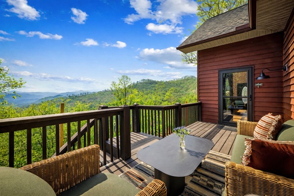A quiet deck with loveseat and chair—an easy spot to settle in and take in the mountain views.