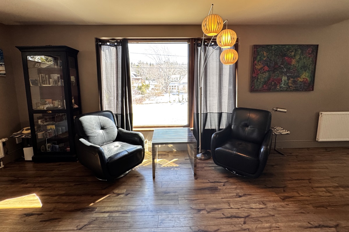 Bright, open landing at the base of the third-floor stairway. This versatile space connects the designer office and the main-level master suite, offering a quiet, sun-drenched area to decompress while overlooking the village of Otter Creek.