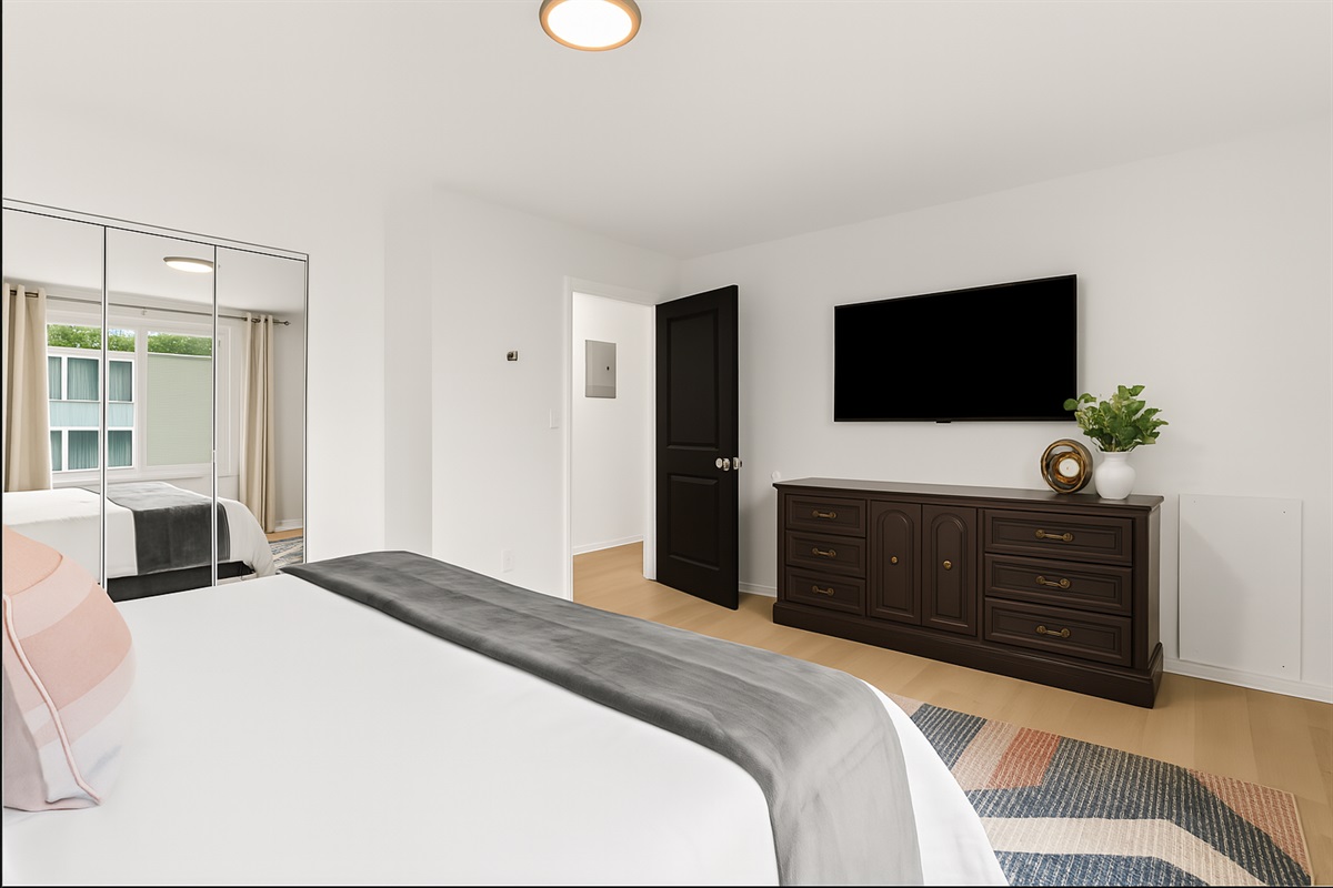 Full bedroom view with relaxing décor, blackout curtains, and private entertainment setup.