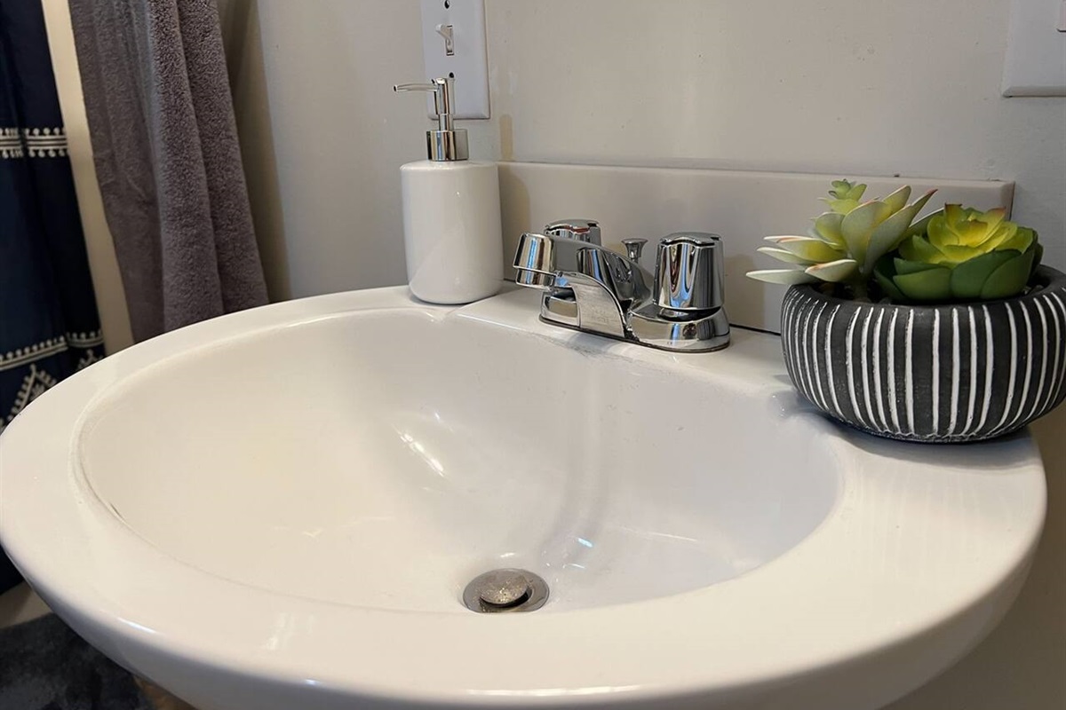 Modern full bathroom featuring a sleek sink with a stylish faucet and tasteful decorations—designed to offer a clean, functional space with a touch of elegance and contemporary charm
