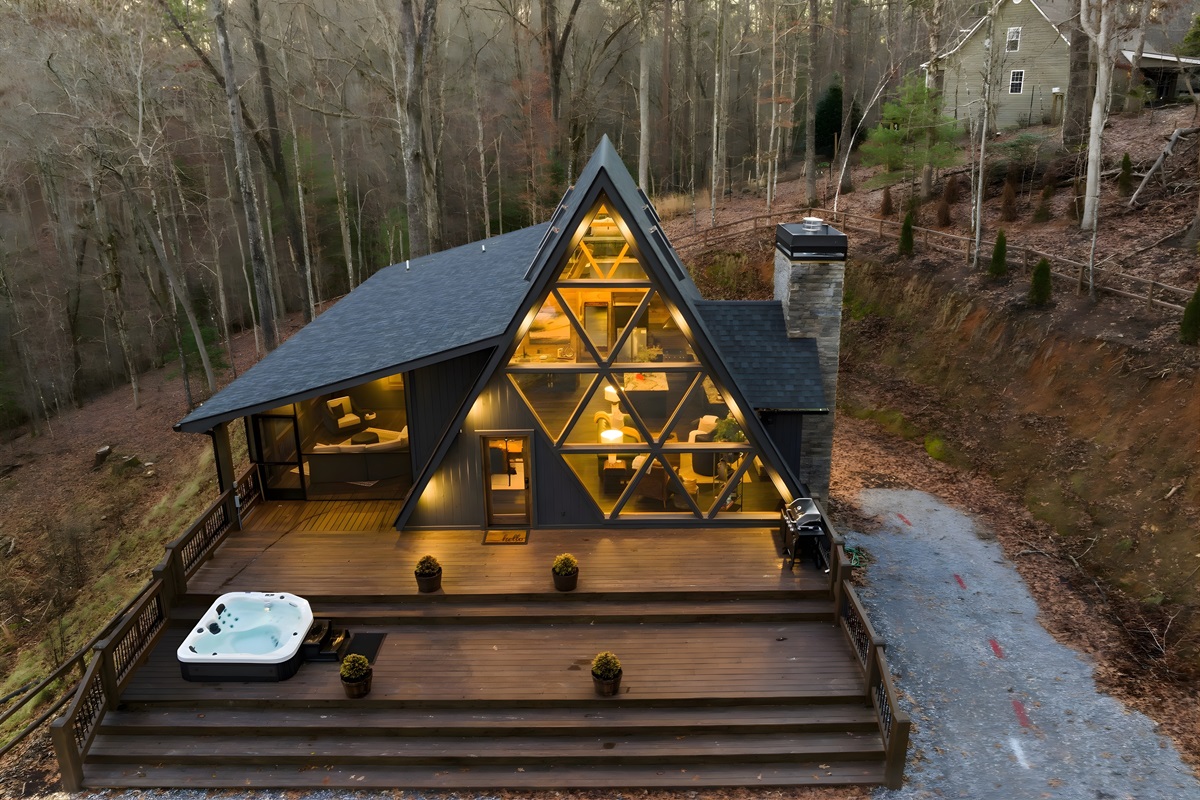 A modern A-frame retreat wrapped in nature, soaring windows, warm light, and peaceful mountain surroundings.
