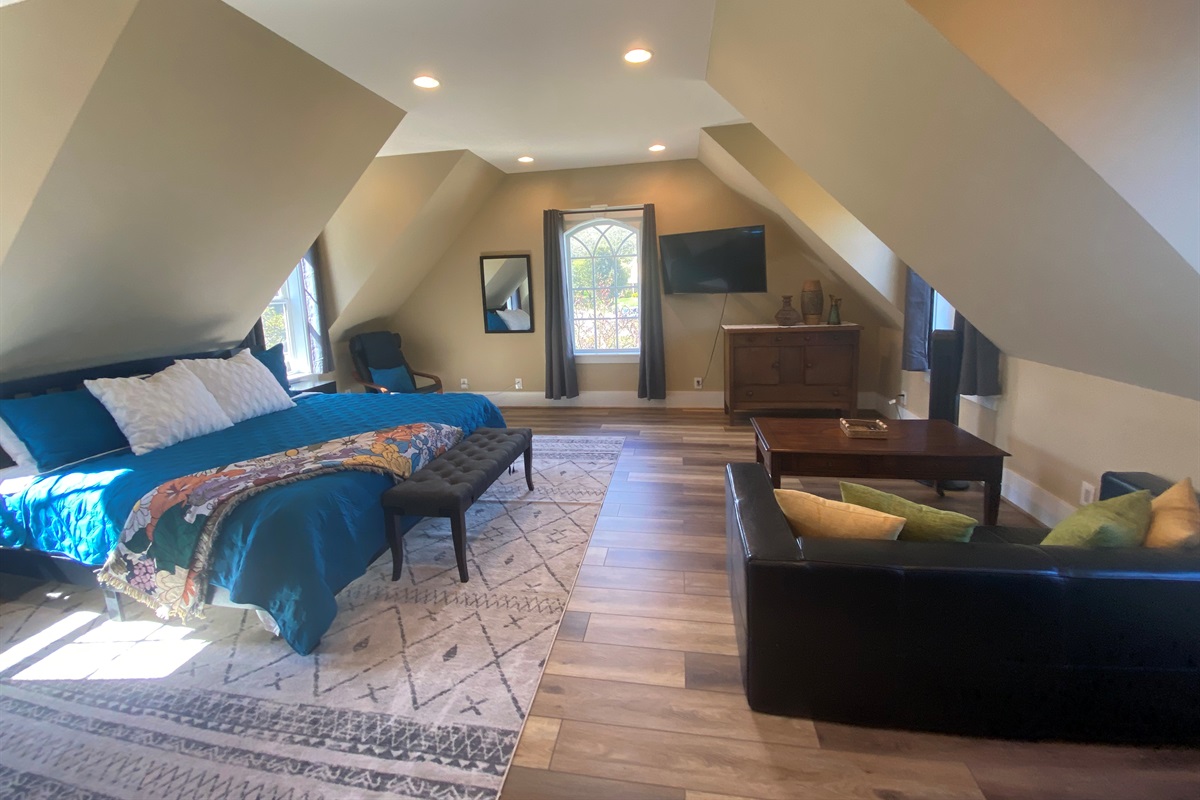 The expansive bonus room above the garage features a king bed, a sitting area, and an office desk. 