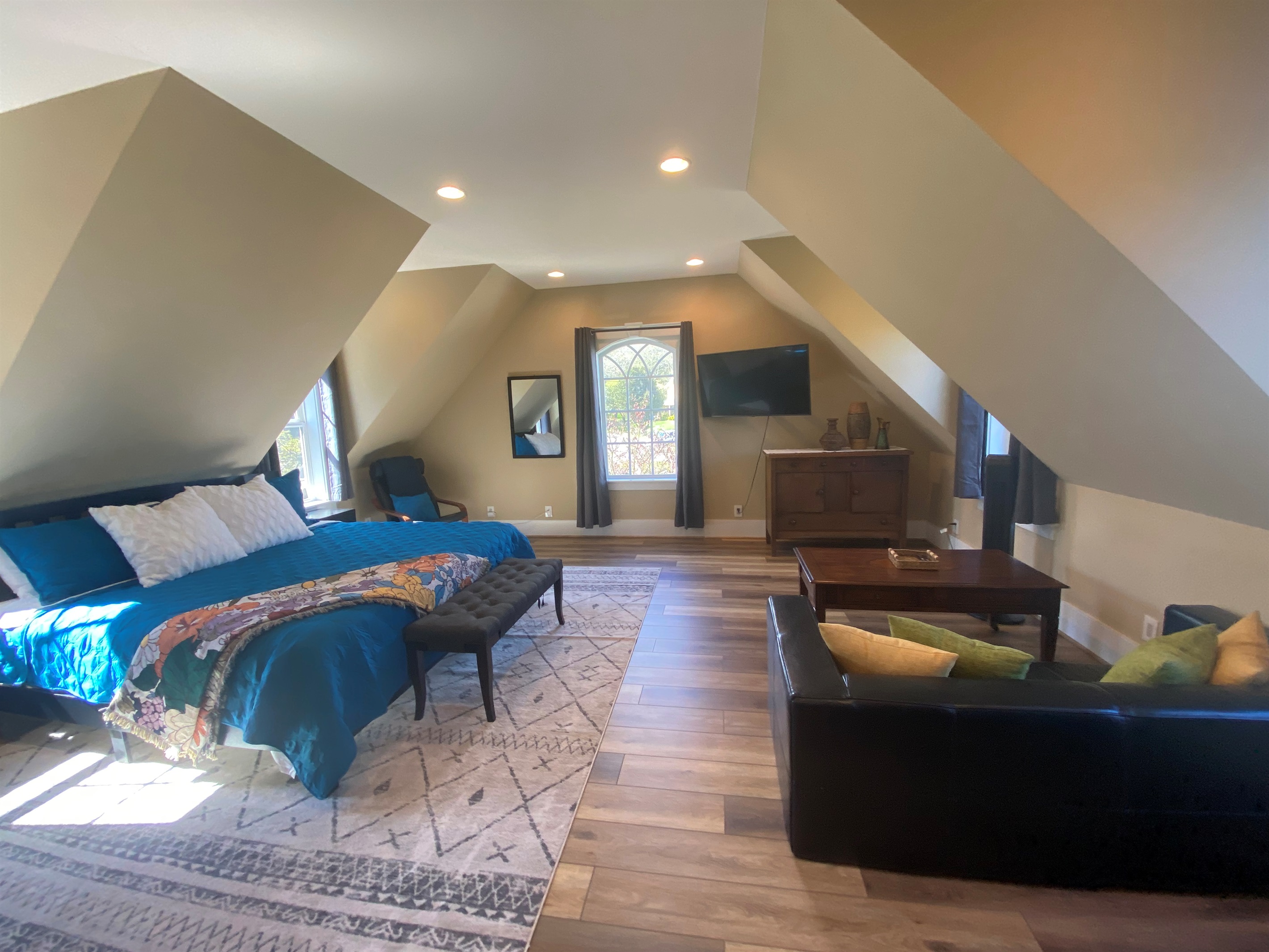 The expansive bonus room above the garage features a king bed, a sitting area, and an office desk. 