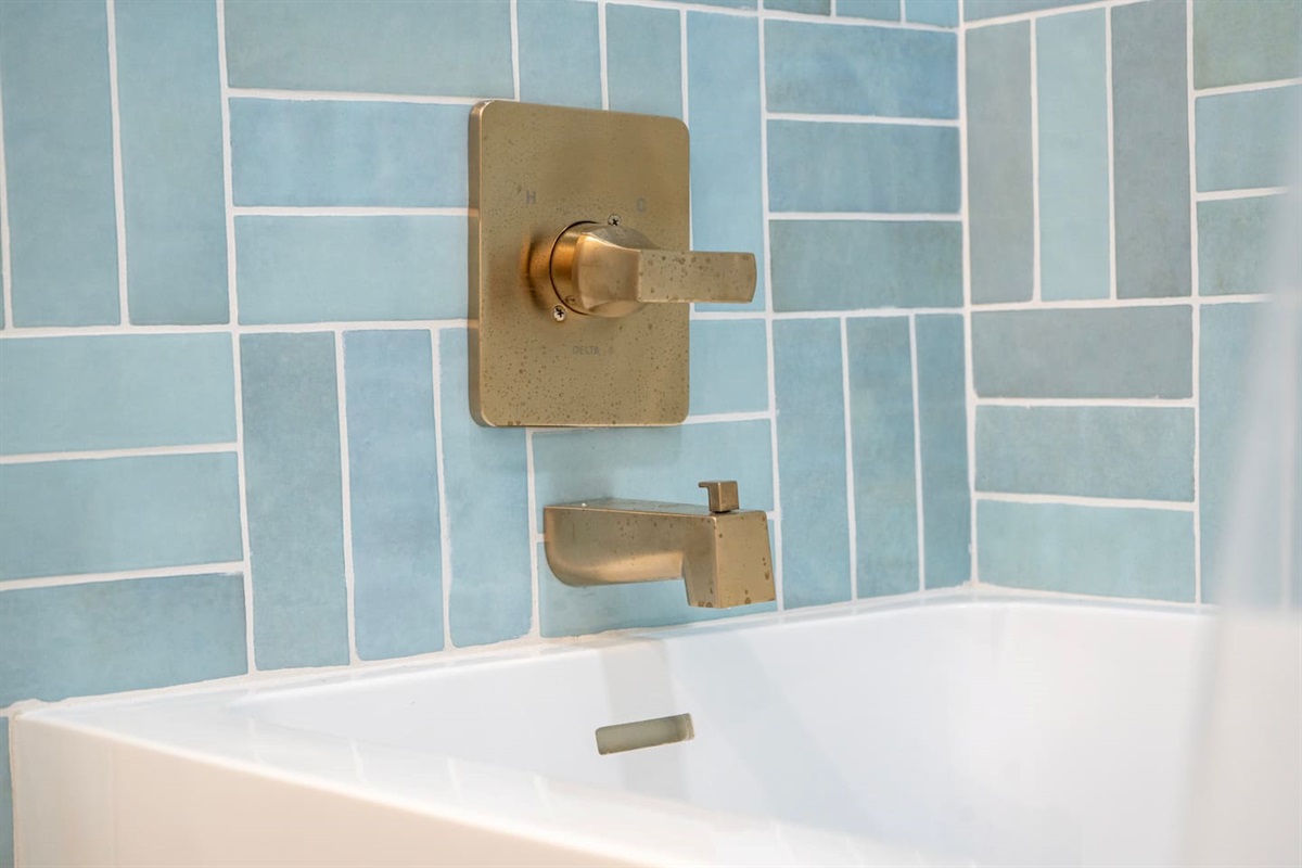 Designer brass fixtures and custom tile create a modern, spa-like shower experience