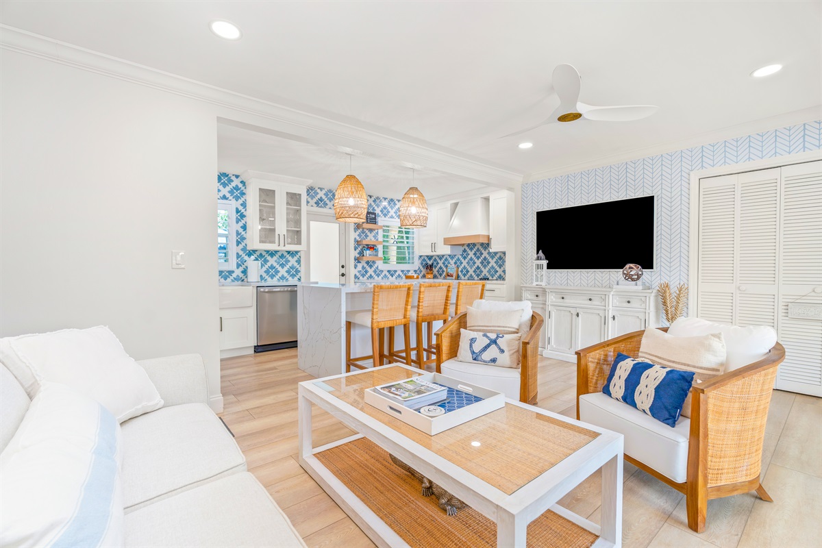 A sunlit living area with a breezy coastal look, offering a comfortable place to unwind and easy access to the kitchen.