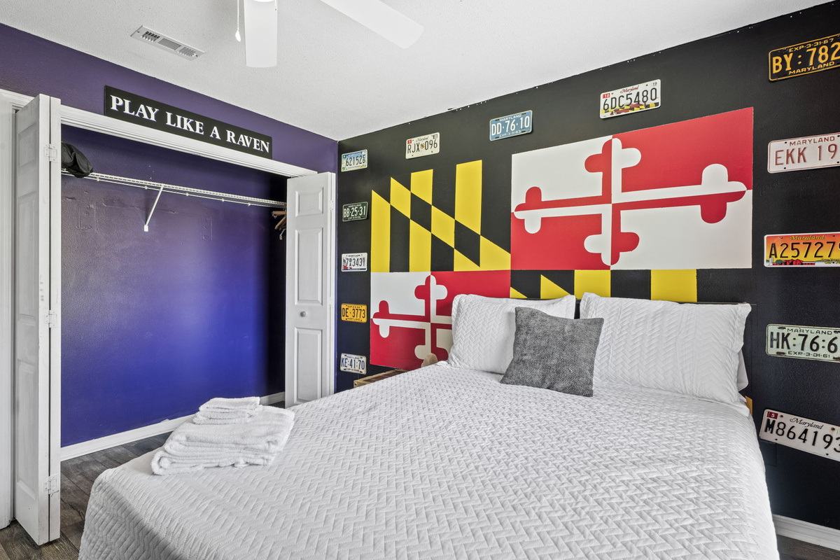 Cozy queen bed set against a striking black-and-flag accent wall, with a closet ready for your beach gear.