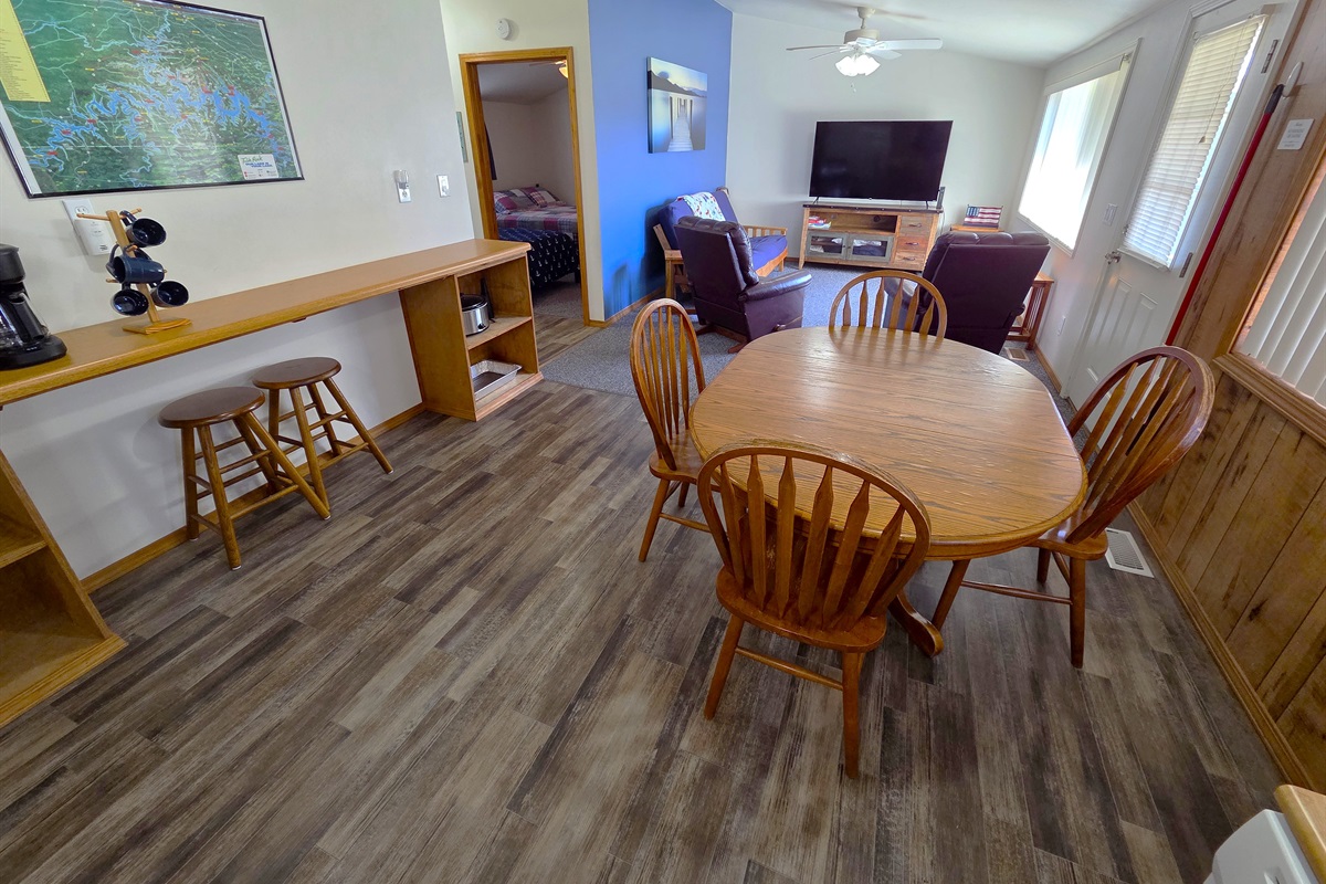 Enjoy a large dining area, and living room with recliners, a futon smart TV, vaulted ceiling, and large picture window overlooking the deck and lake.