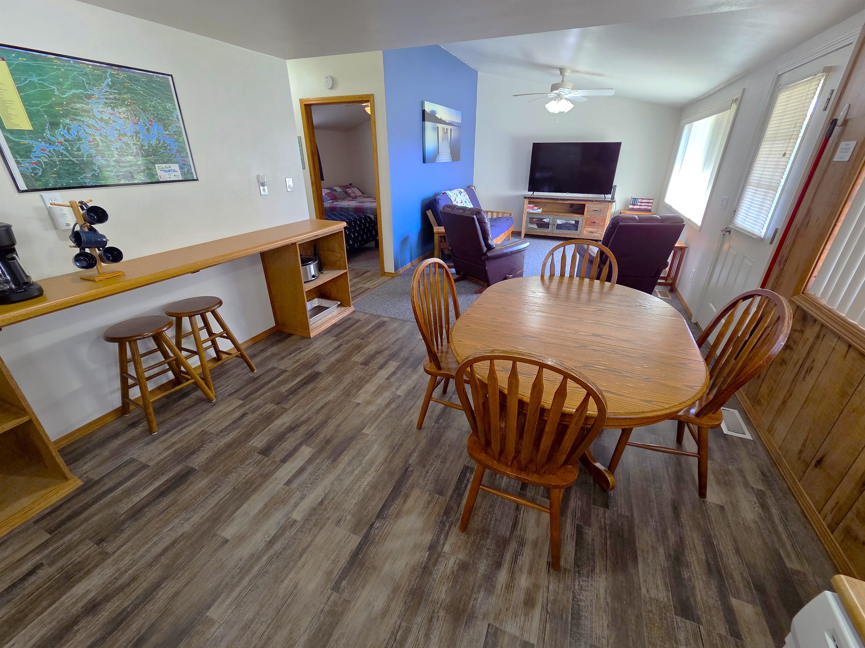 Enjoy a large dining area, and living room with recliners, a futon smart TV, vaulted ceiling, and large picture window overlooking the deck and lake.