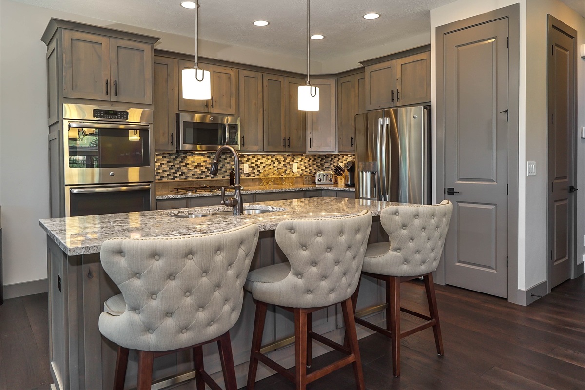 Modern kitchen with granite countertops and stylish bar seating for 3.