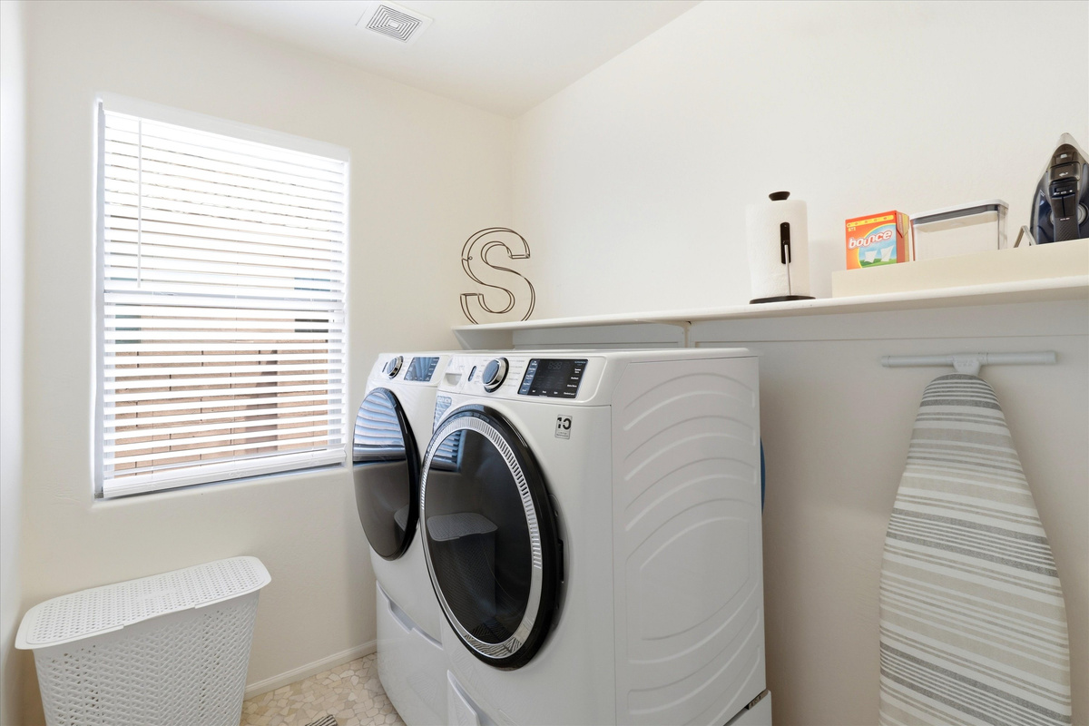 Laundry room with washer, dryer, shelf storage, and supplies for longer stays.
