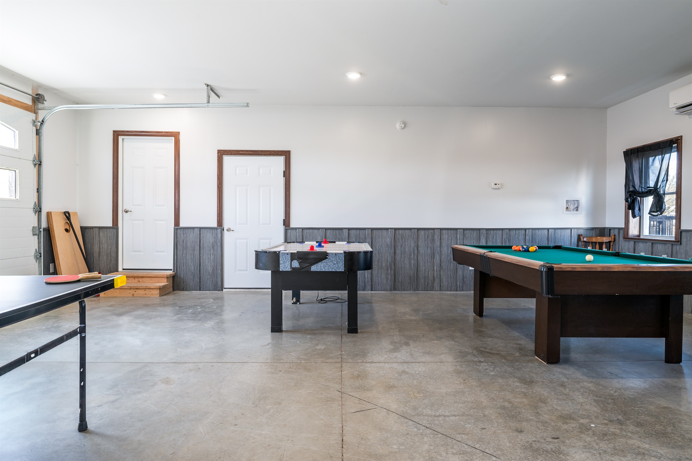 Bright rec room with garage access, perfect for casual hangouts, games, and laughter. Relax, recharge, and have fun indoors!