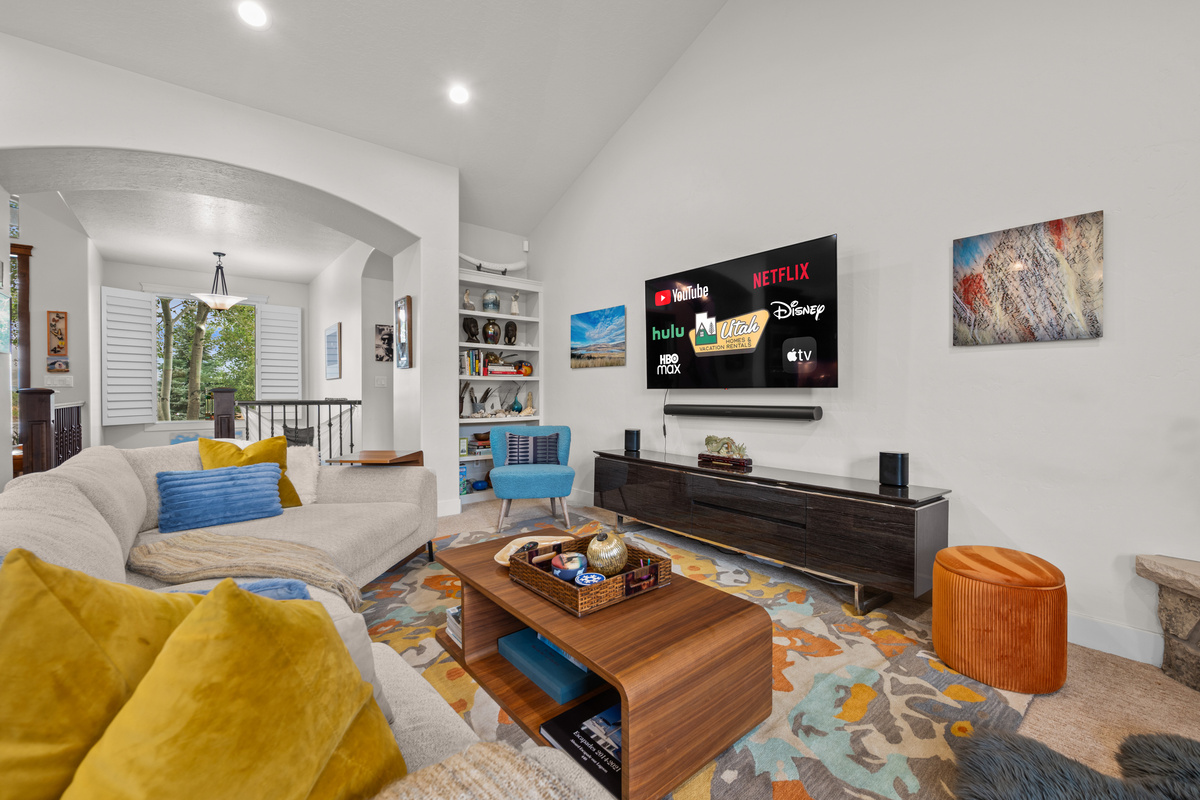 Relax in the spacious great room featuring soaring ceilings, a large Smart TV with streaming services, plush seating, and an open layout perfect for movie nights and family gatherings.
