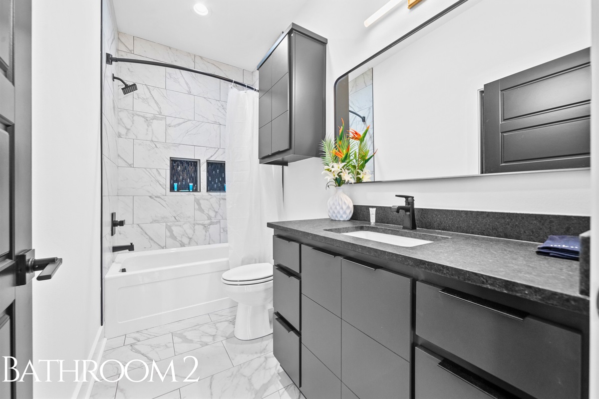 A fresh and contemporary bathroom with elegant tilework, a shower-tub combination, and bright lighting that adds both style and convenience.