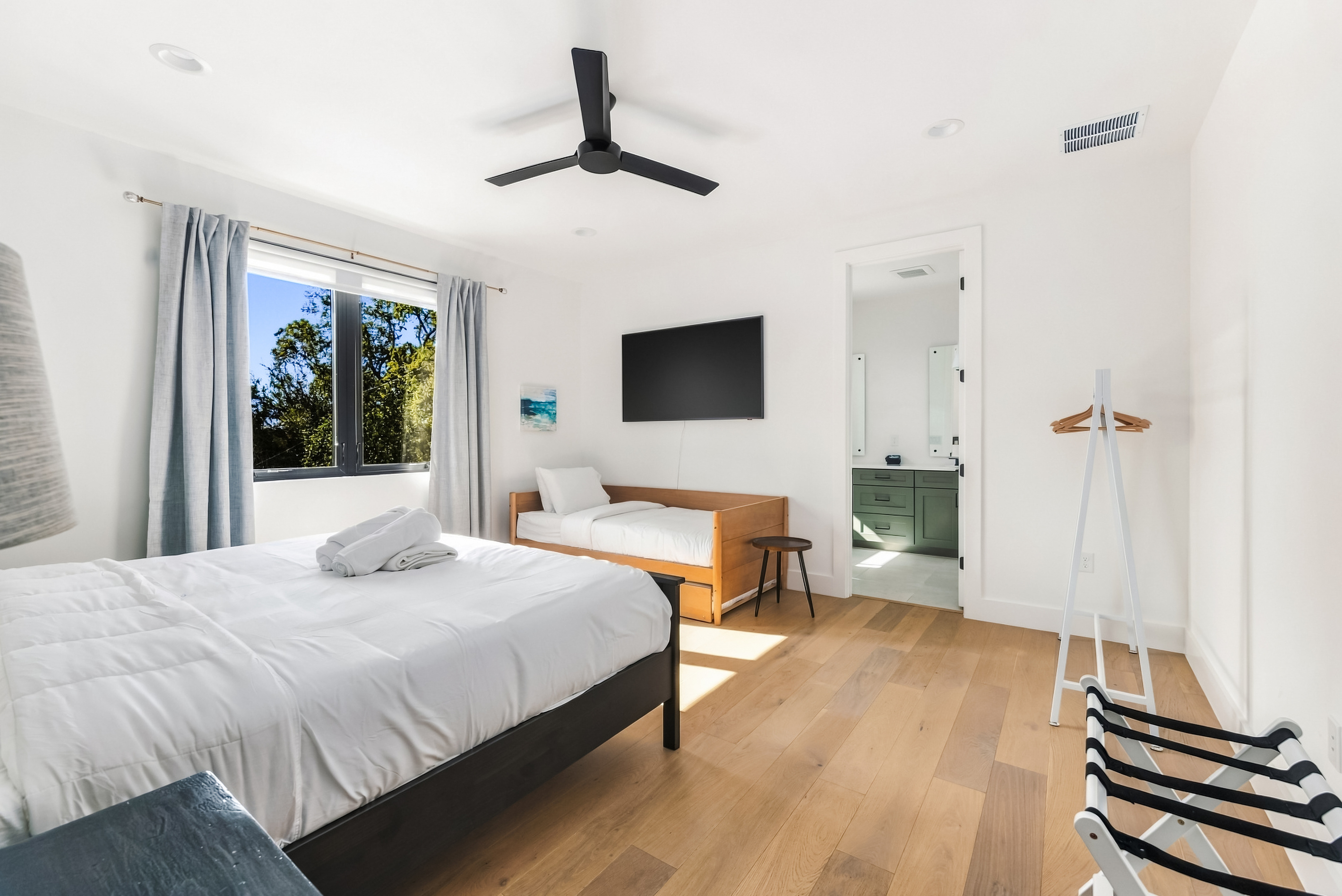 Primary suite with plush bedding, ceiling fan, and an en-suite bathroom.