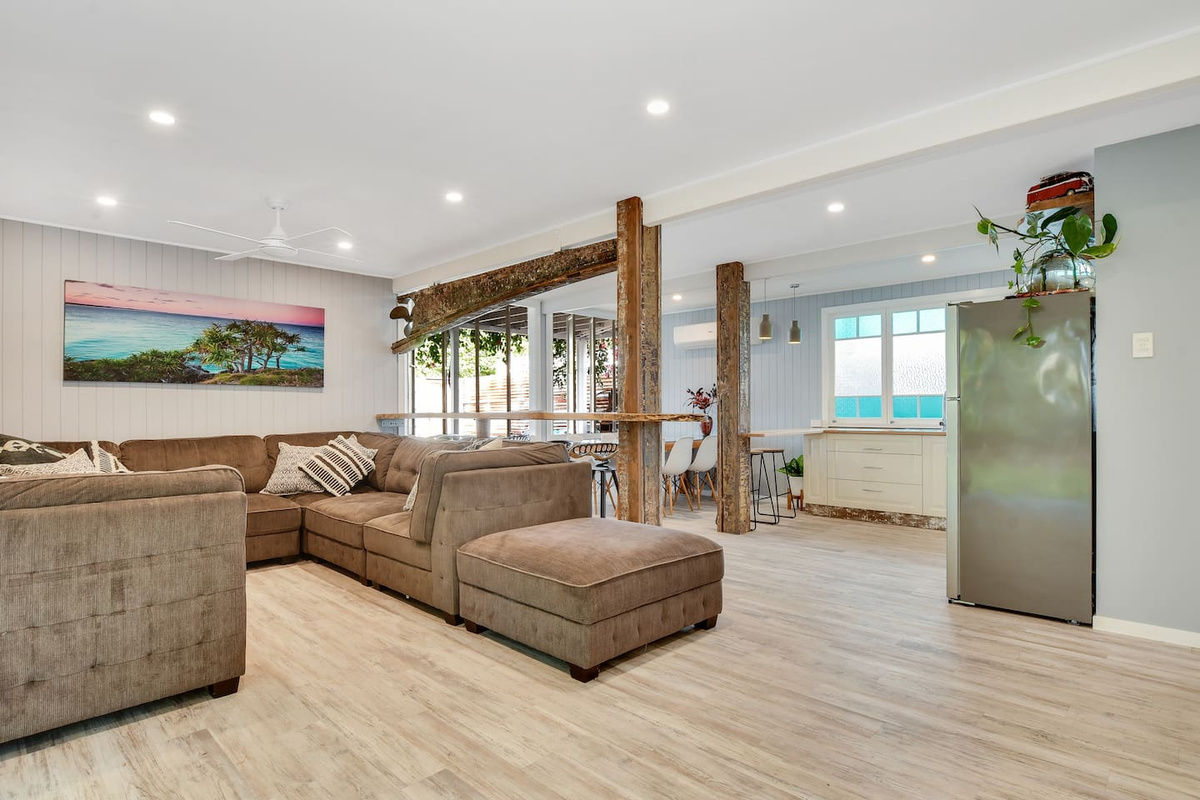 The ground-floor living area at Aaron's Beachside Boat House combines a generous sectional lounge with an adjoining kitchen and dining zone in one open layout.